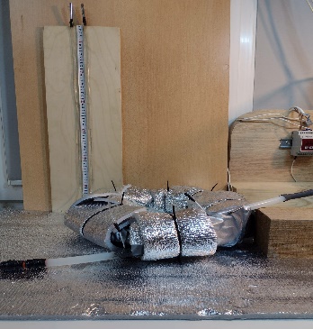 Выборочные фрагменты малогабаритного гидравлического стенда с скрученным и помещенным в защитный кожух трубопровод и панно с мерной линейкой